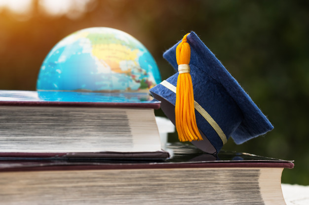 blue-graduation-cap-opening-textbook-with-blur-america-earth-world-globe-model-map-library-room-campus